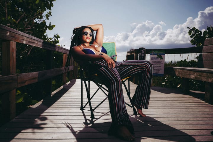 woman in shades laying back in the sun on a wooden pier